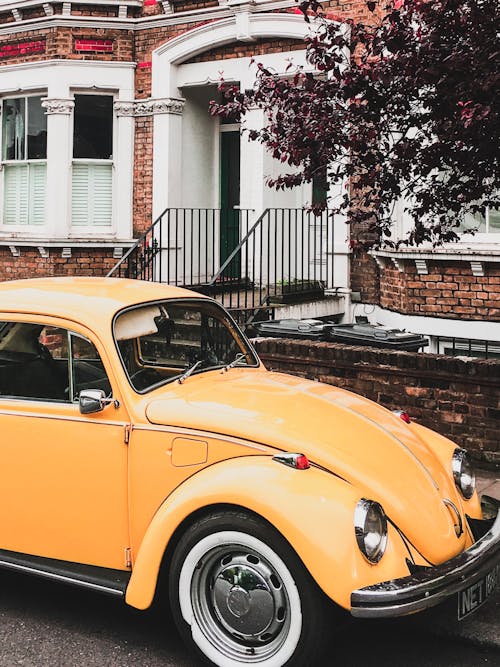 Free Photo of Yellow VW Beetle Parked by the Curb Next to a House Stock Photo