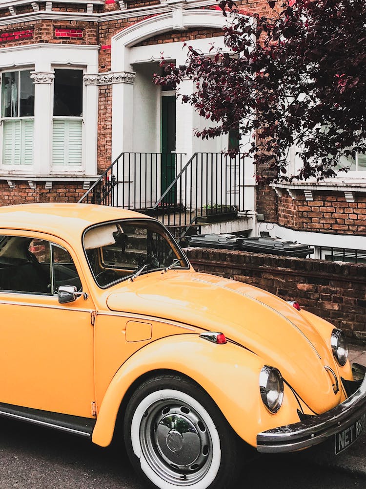 Photo Of Yellow VW Beetle Parked By The Curb Next To A House