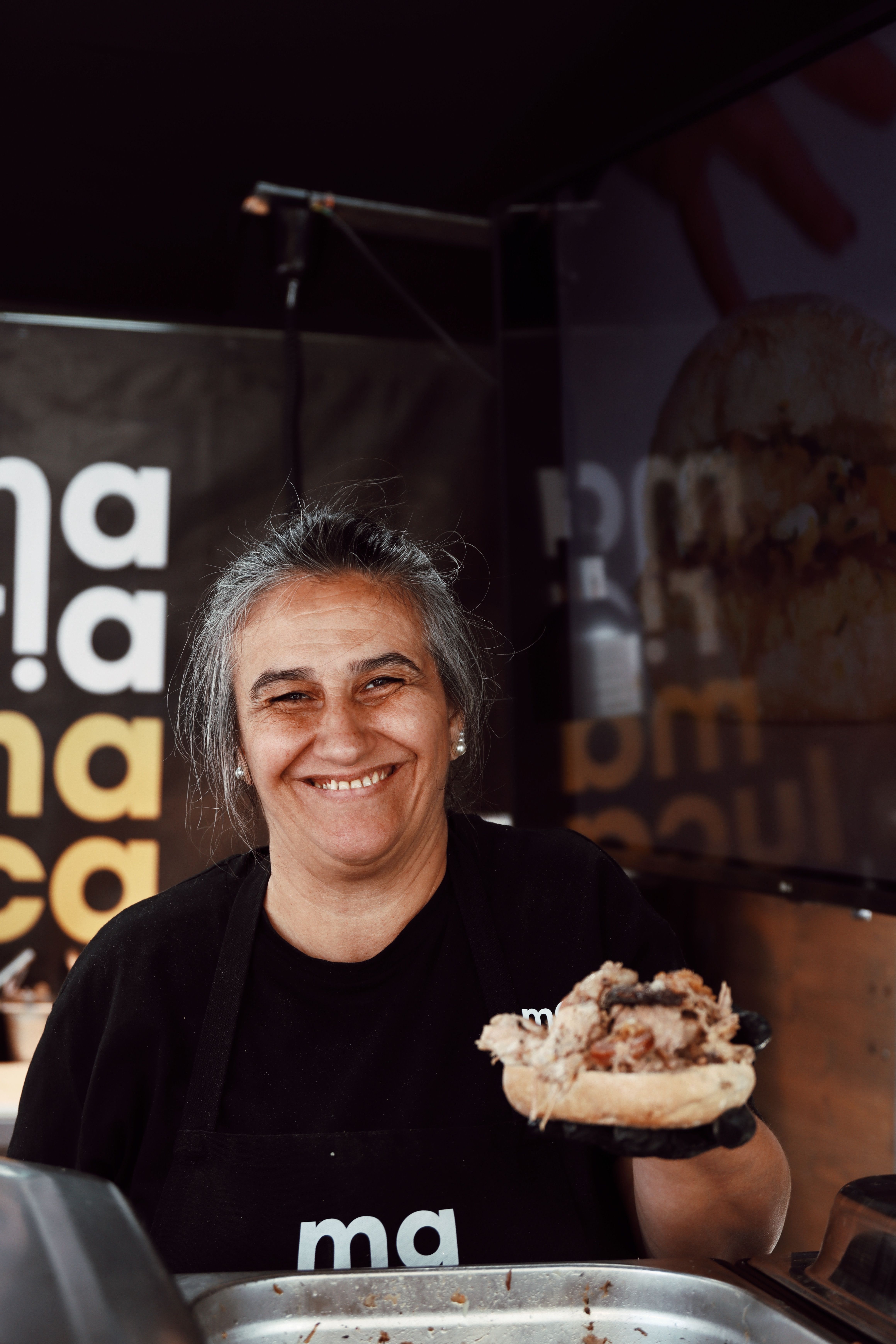 A cheerful chef serving a sandwich at a street food truck in Lisbon, Portugal.