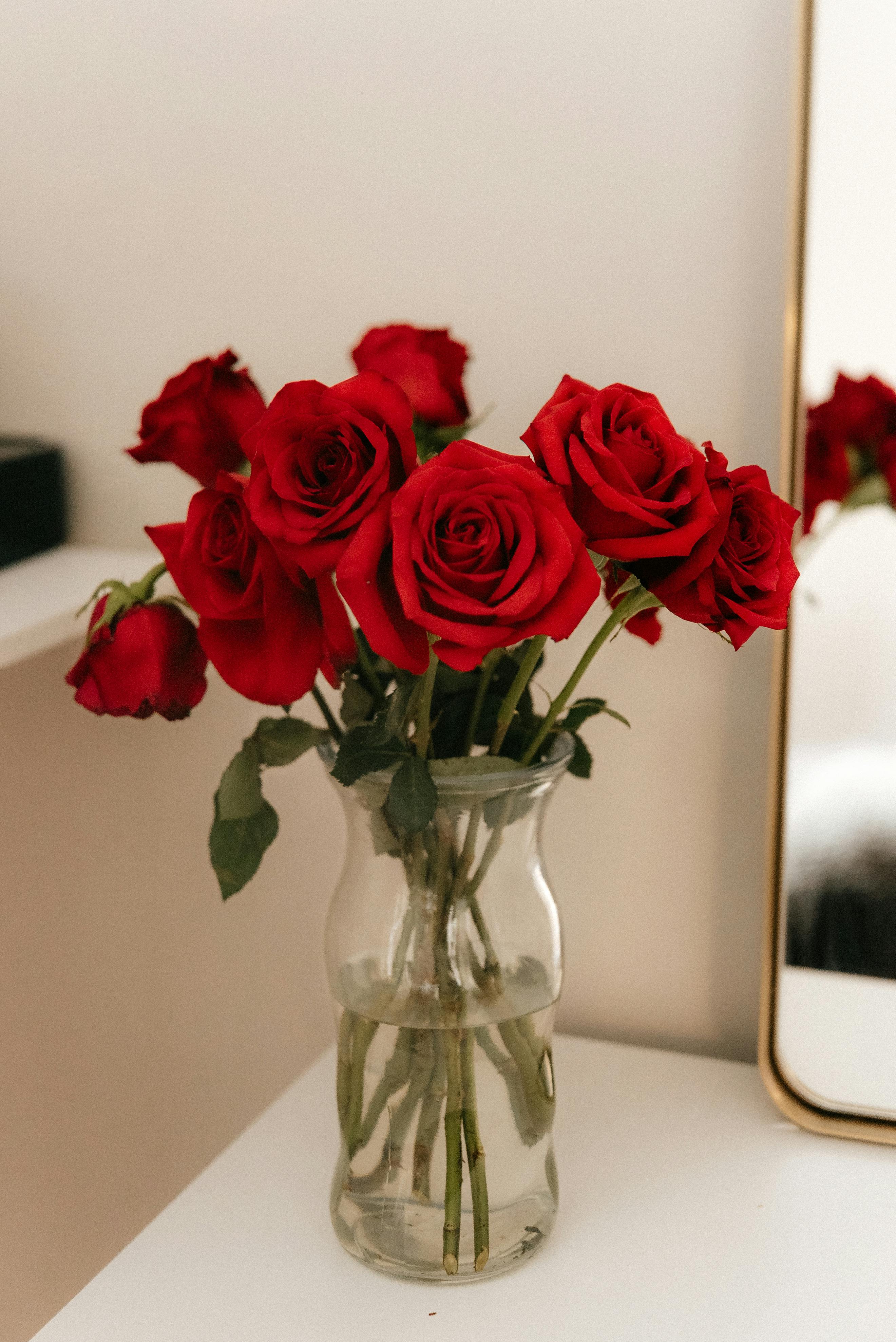 A beautiful arrangement of red roses in a glass vase, perfect for romantic settings.