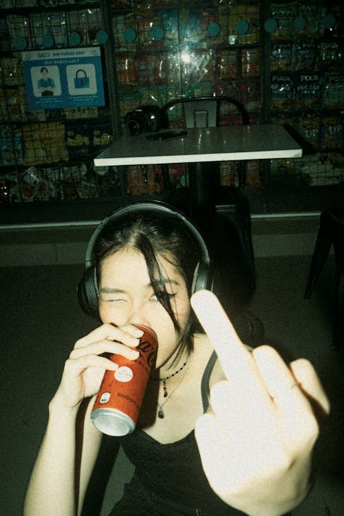 A woman with headphones and a can of soda