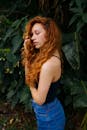 侧面轮廓是一位红发卷曲的美丽女子，站在生机盎然的树叶前