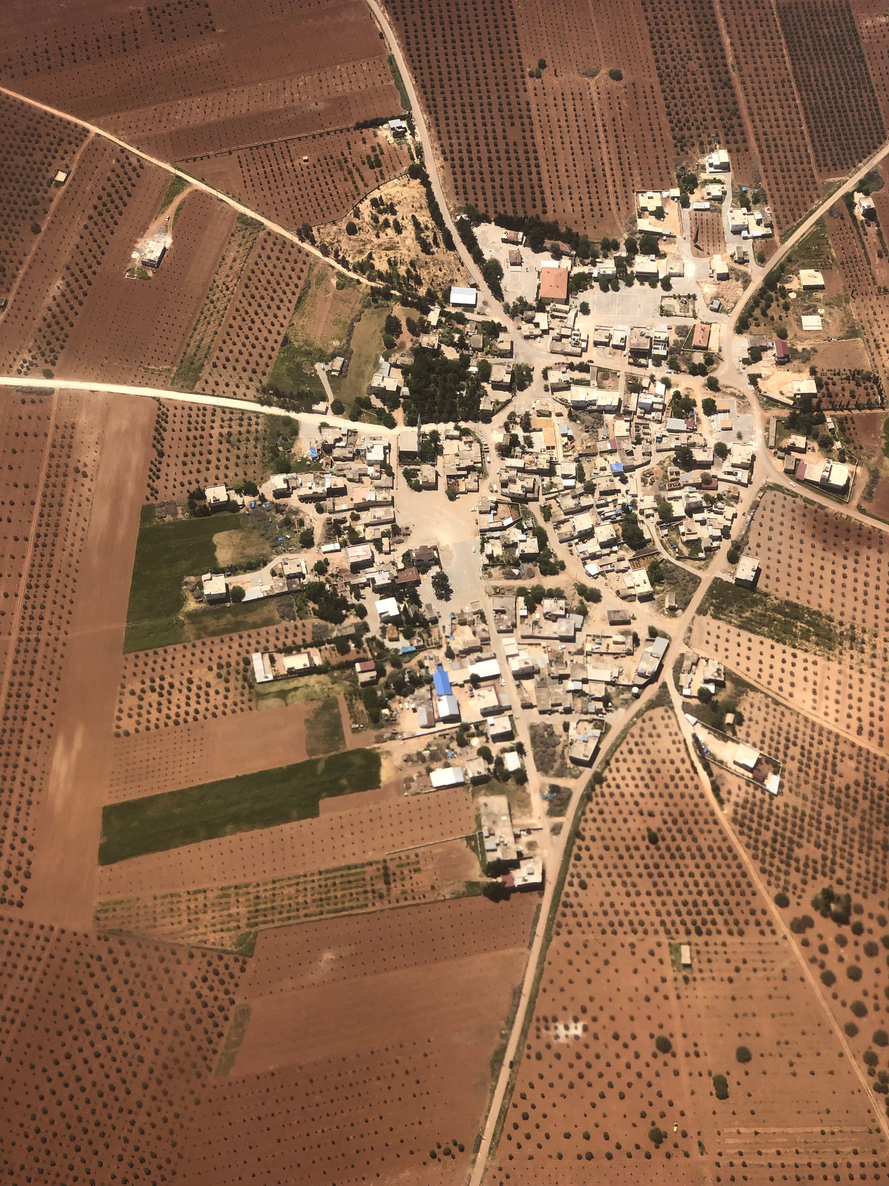 Aerial shot of a rural village surrounded by farmland, showcasing agriculture and landscape.