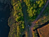 从空中俯瞰，蜿蜒的道路穿过郁郁葱葱的森林，一旁是宁静的湖泊，景色令人惊叹