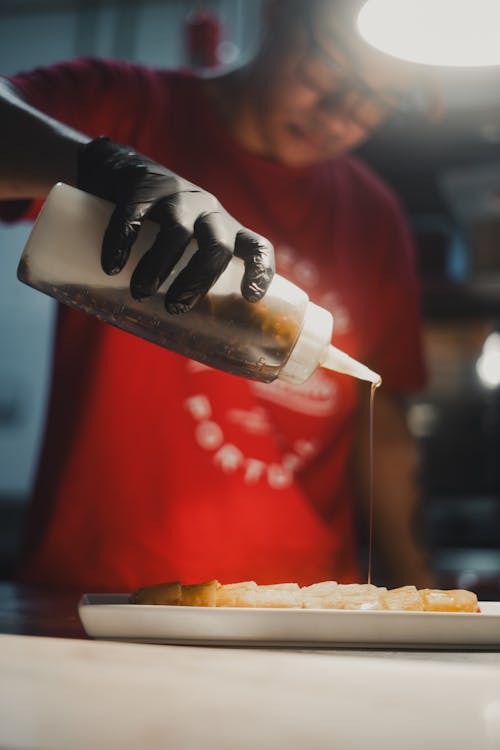 A person pouring syrup on a plate