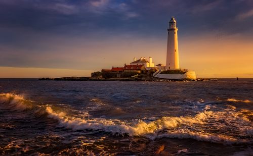 Free A mesmerizing view of St Mary's Lighthouse at sunset with waves crashing on the shore, located on the coast of England. Stock Photo