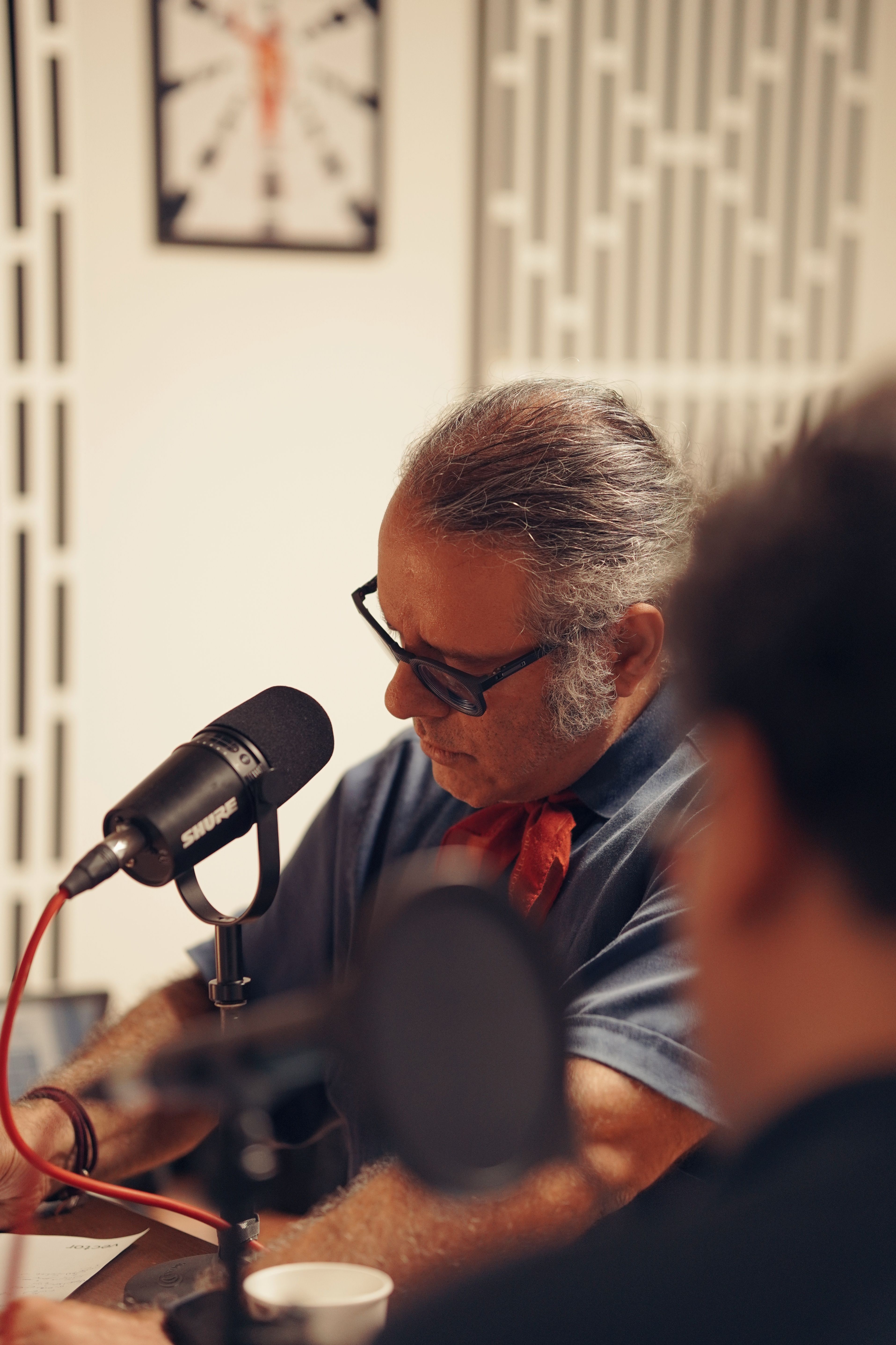 A man in a studio speaking into a microphone, engaging in podcasting.