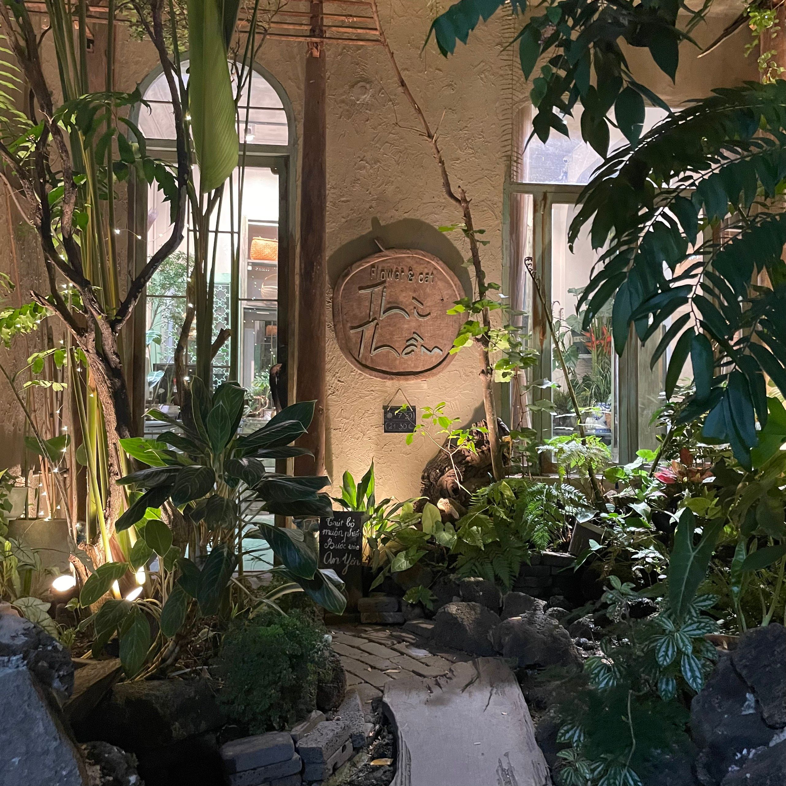 A warm, inviting indoor garden café setting with lush greenery.