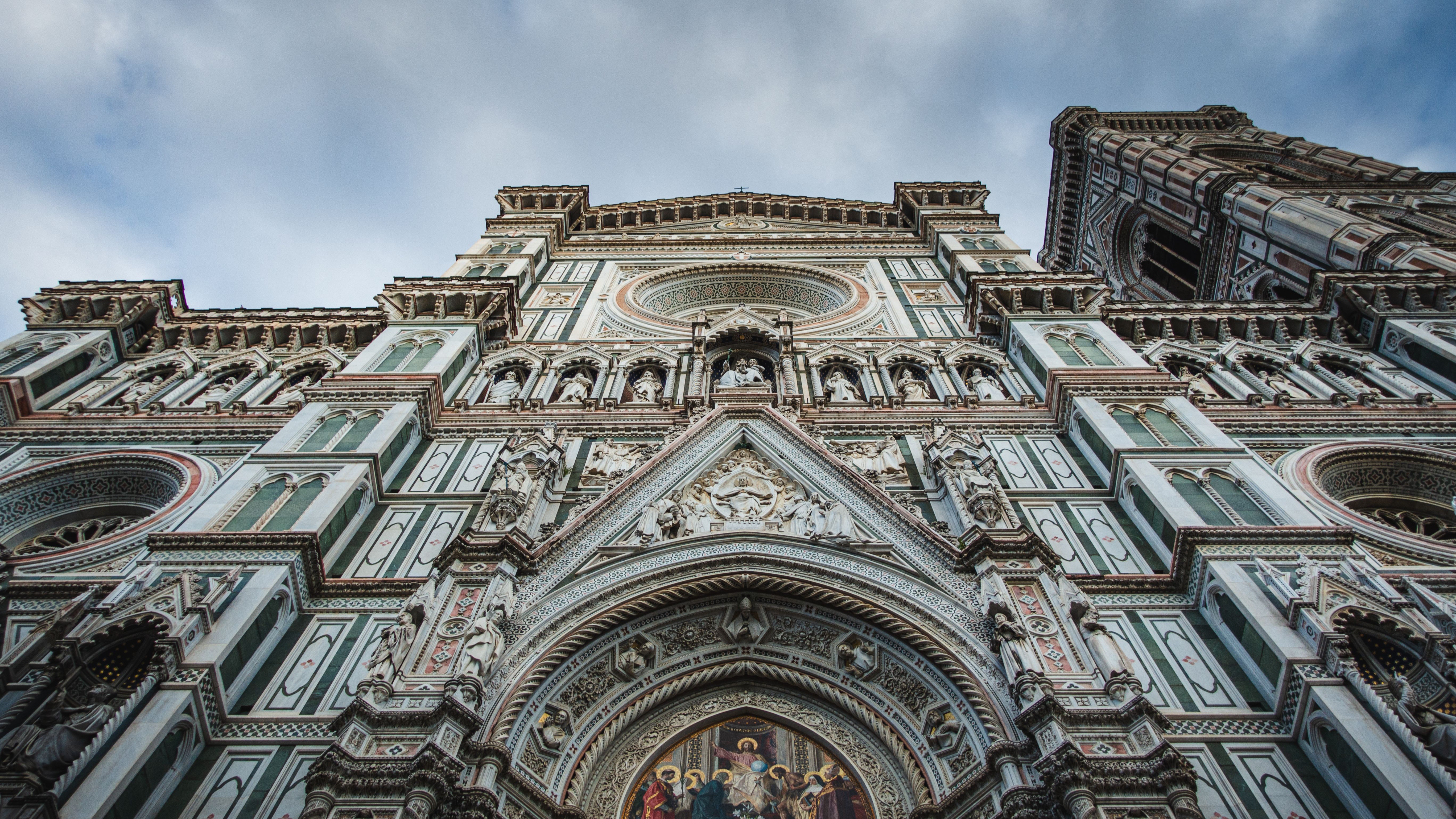 Low angle view of the stunning Gothic facade of Florence Cathedral against a cloudy sky.