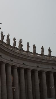Majestic statues atop the Vatican's St. Peter's Basilica colonnade captured in a vertical shot.