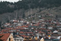 An elevated view of a town with red rooftops nestled in a mountainous area, showcasing urban and natural harmony.