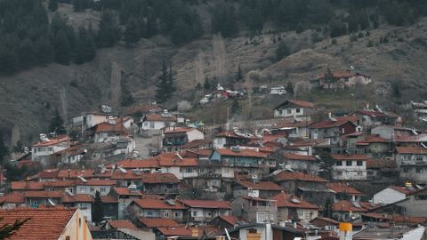 An elevated view of a town with red rooftops nestled in a mountainous area, showcasing urban and natural harmony.