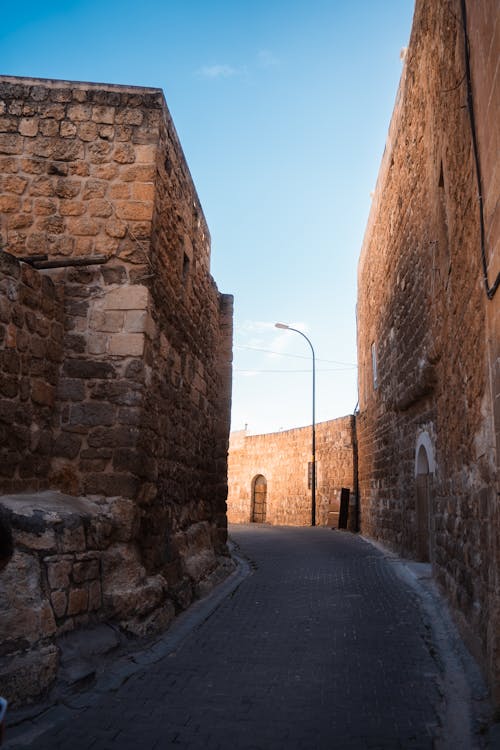 A narrow alley with stone walls and a blue sky