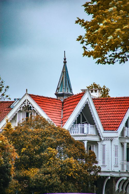Free A picturesque Victorian style house with a distinctive red tiled roof and intricate architectural details. Stock Photo