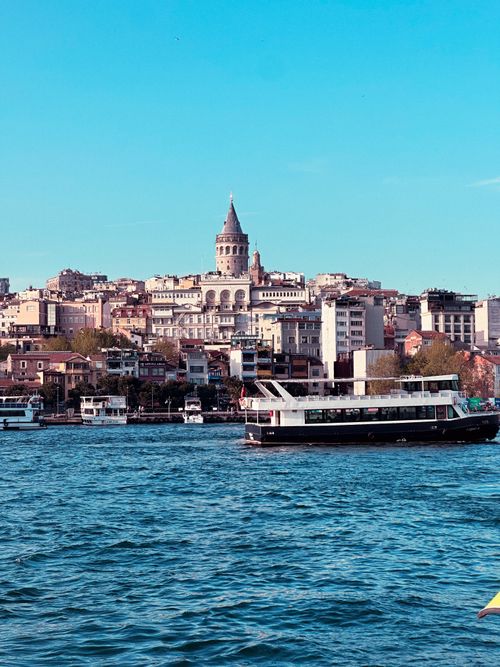 Free A serene view of Istanbul's Galata Tower and ferry on the Bosphorus under a clear sky. Stock Photo