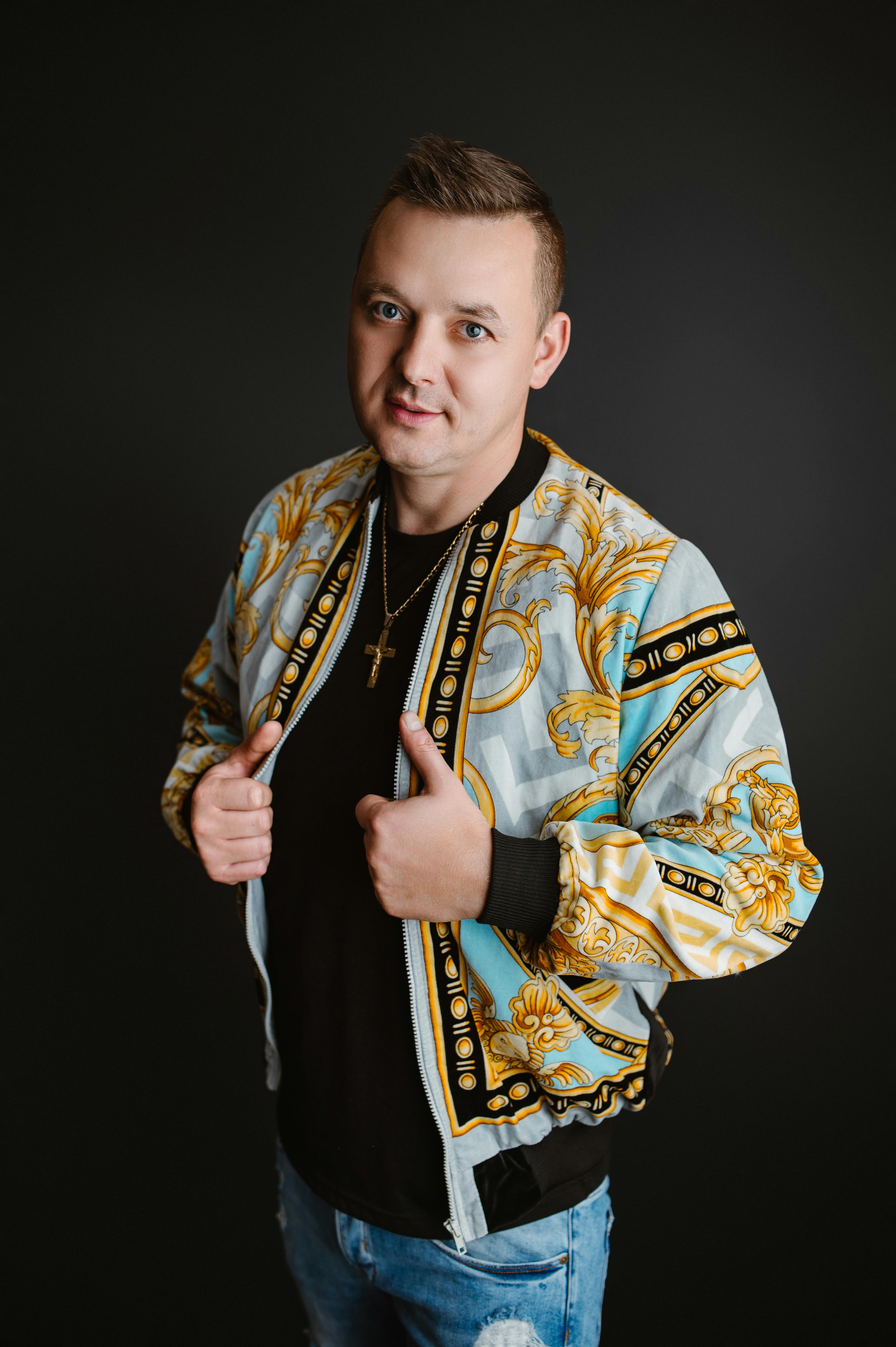 A studio portrait of a man wearing a stylish jacket against a dark background.