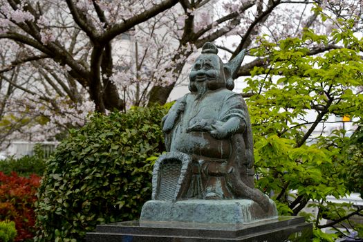 Bronze statue surrounded by spring foliage in an urban park.