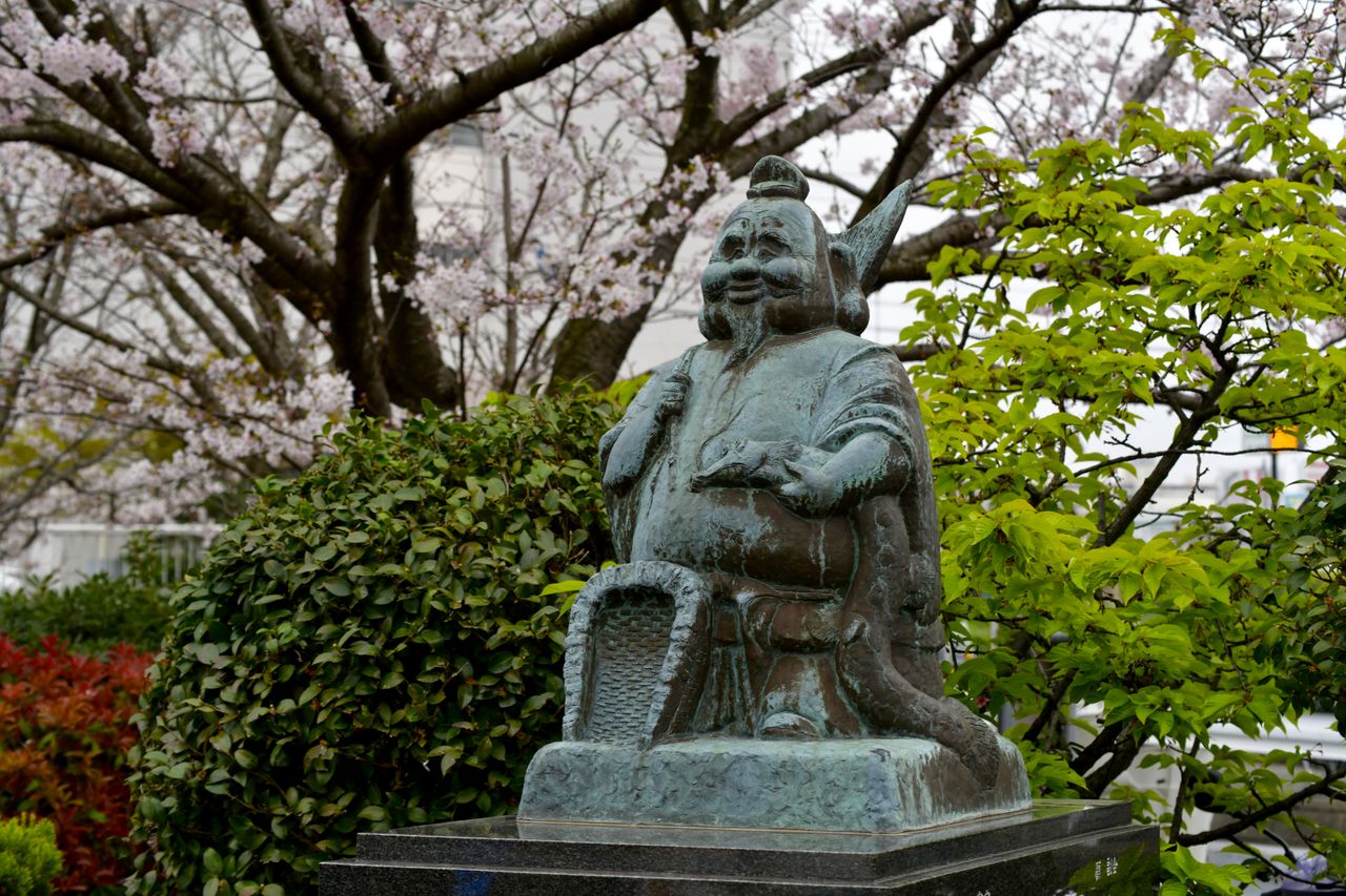 bronze statue surrounded by spring foliage in an urban park