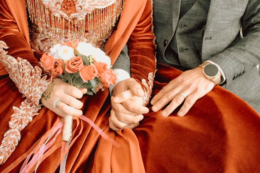 Close-up of a couple in traditional Turkish wedding attire holding hands with a bouquet.