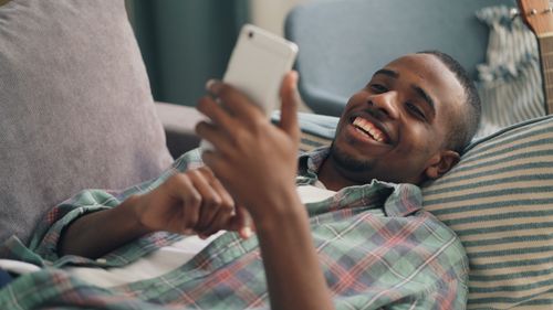 Free A young man enjoying leisure time at home while using a smartphone. Stock Photo