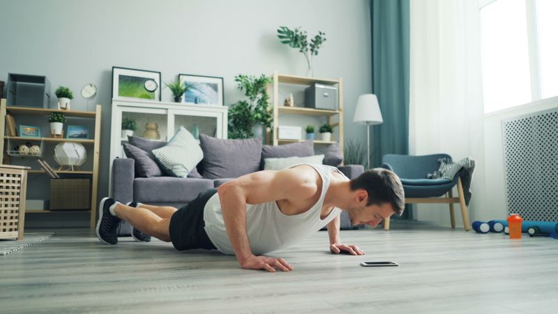Man doing bodyweight push-ups in a modern living room - fun home workout routine
