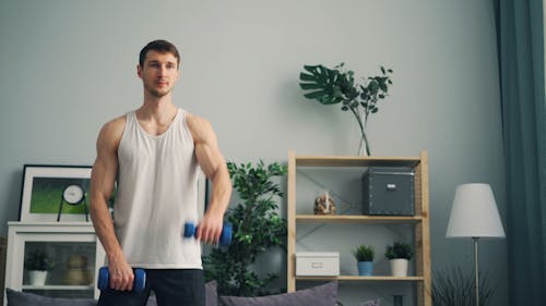 A man is doing exercises with dumbbells in his living room