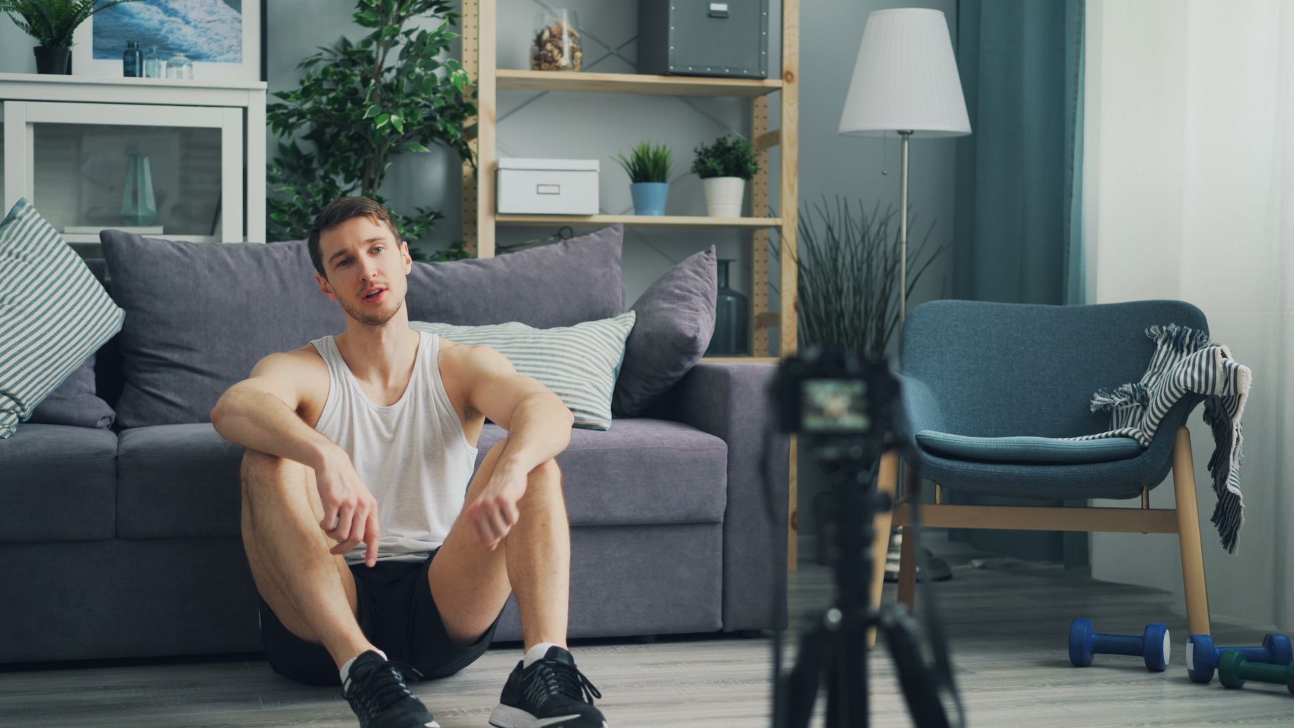 Casual indoor scene of a man relaxing in sportswear with home recording equipment.