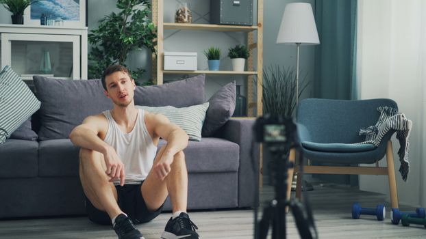 Casual indoor scene of a man relaxing in sportswear with home recording equipment.