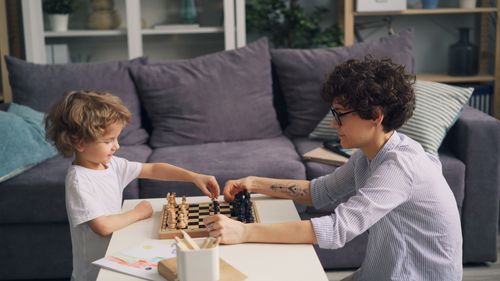 Free A mother and son bonding over a chess game in a cozy living room setting. Stock Photo