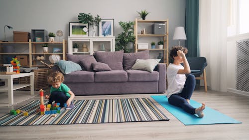 A woman and child are doing yoga in a living room