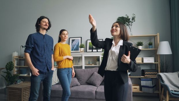 Real estate agent presenting a modern apartment to potential buyers in a stylish living room.