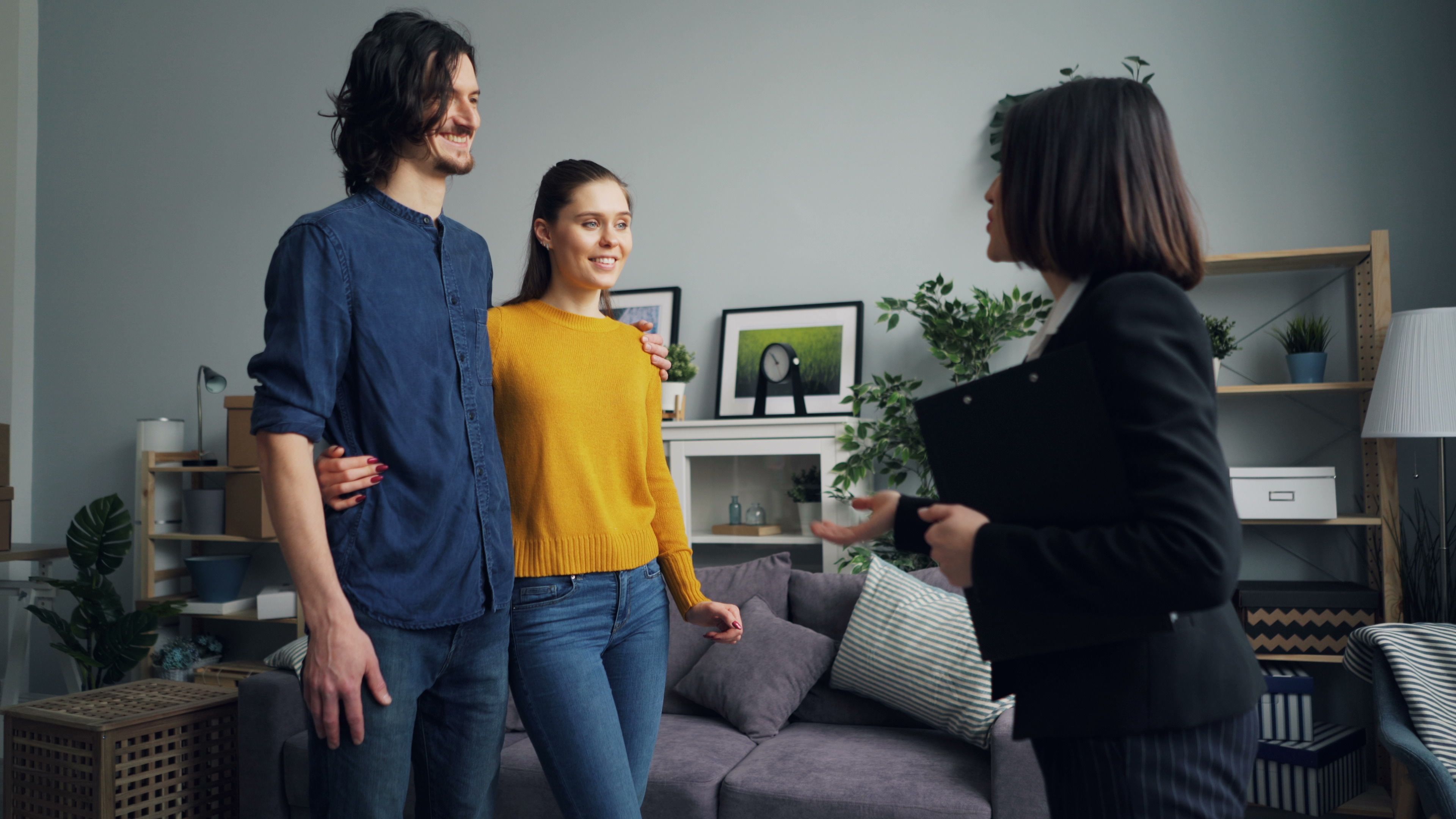 Young couple meeting with a real estate agent in a stylish indoor setting, discussing house options.