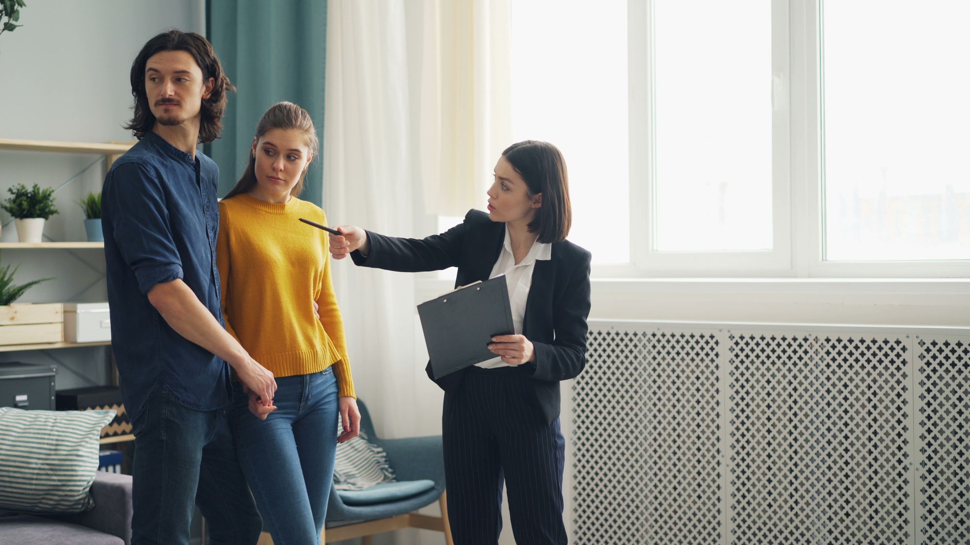 Property adviser showing a bright home to a couple