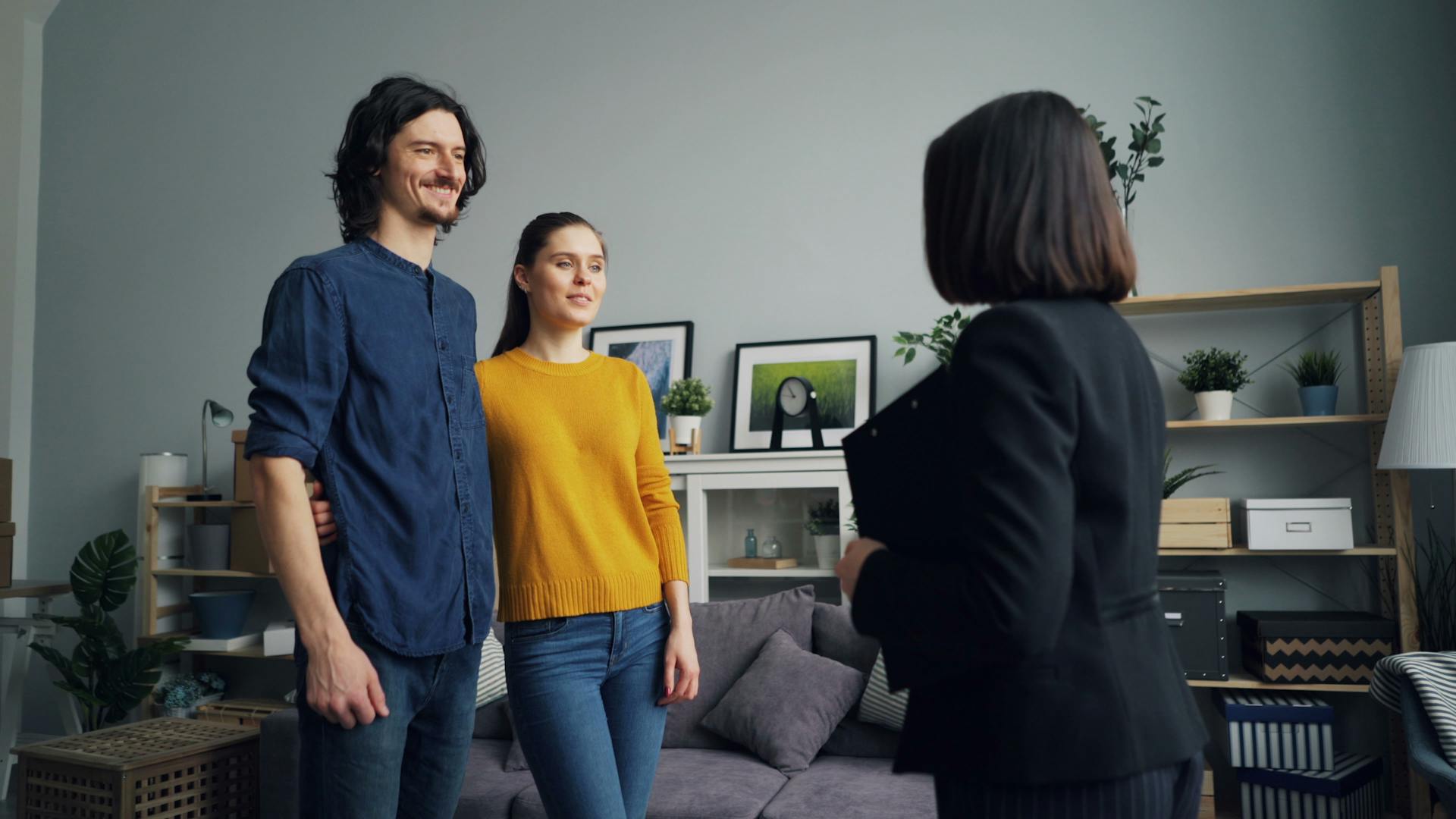 A smiling couple meets with a real estate agent in a stylish living room setting.