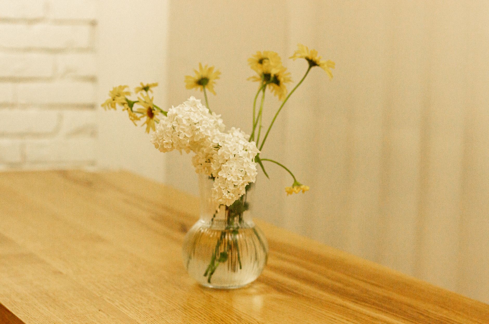 A minimalist arrangement of flowers in a glass vase on a stylish wooden table, perfect for modern interiors.