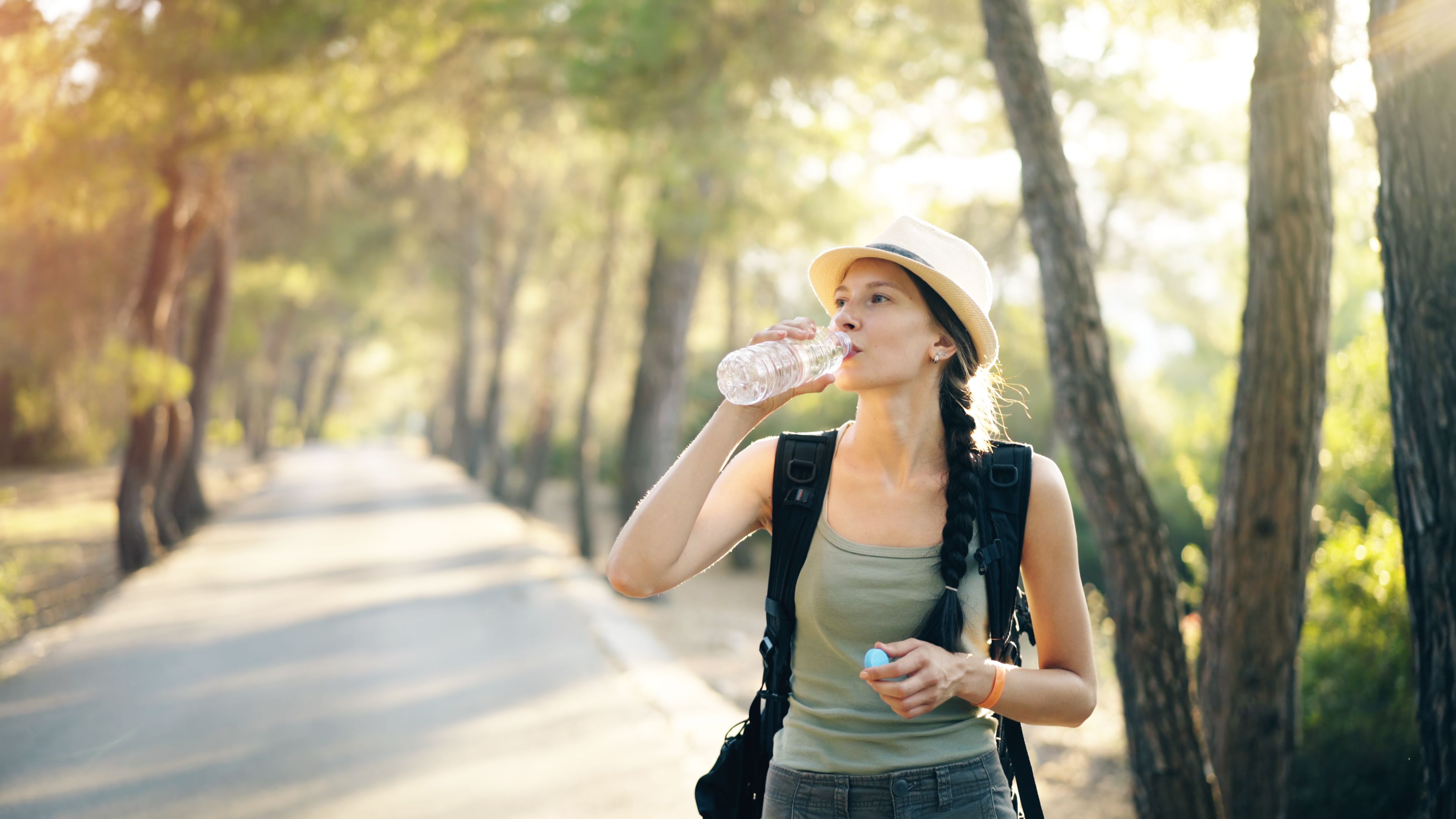 Young woman enjoying a forest hike, drinking water from a bottle