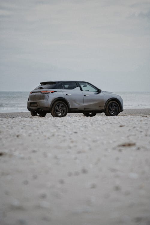 A grey suv parked on the beach near the ocean