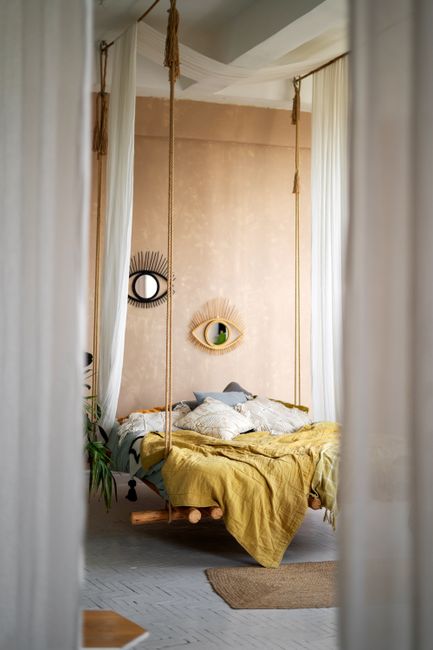 Tranquil modern bedroom featuring a unique hanging bed and artistic eye decor in soft tones.