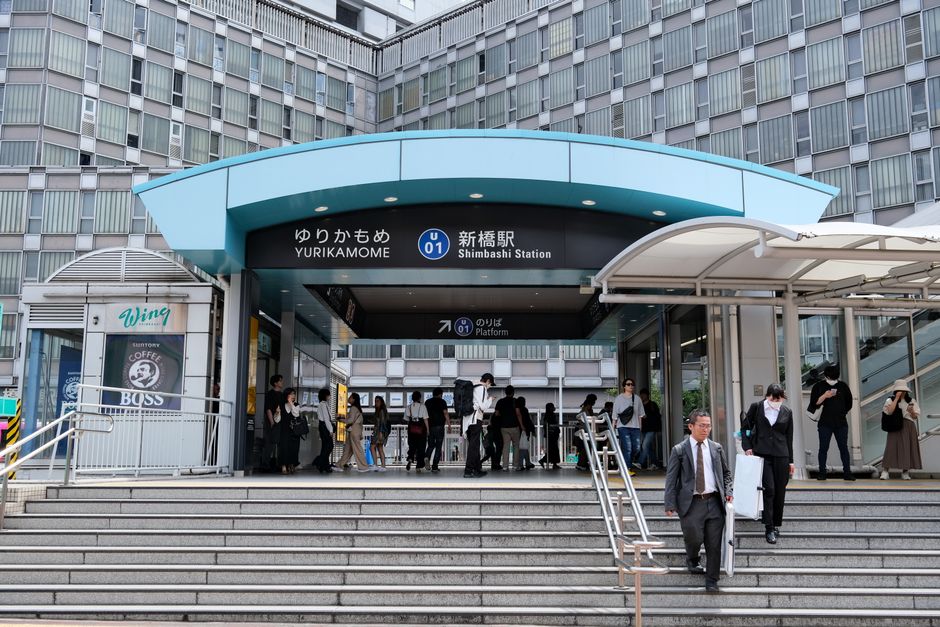 新橋駅の入口で歩いている人々、東京の現代的な都市建築を展示しています。