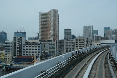 A train is traveling down a track with tall buildings in the background