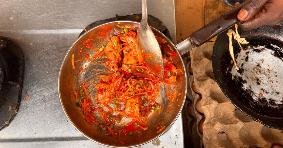 anchovy paste tube being squeezed into a saucepan with tomato sauce and onions