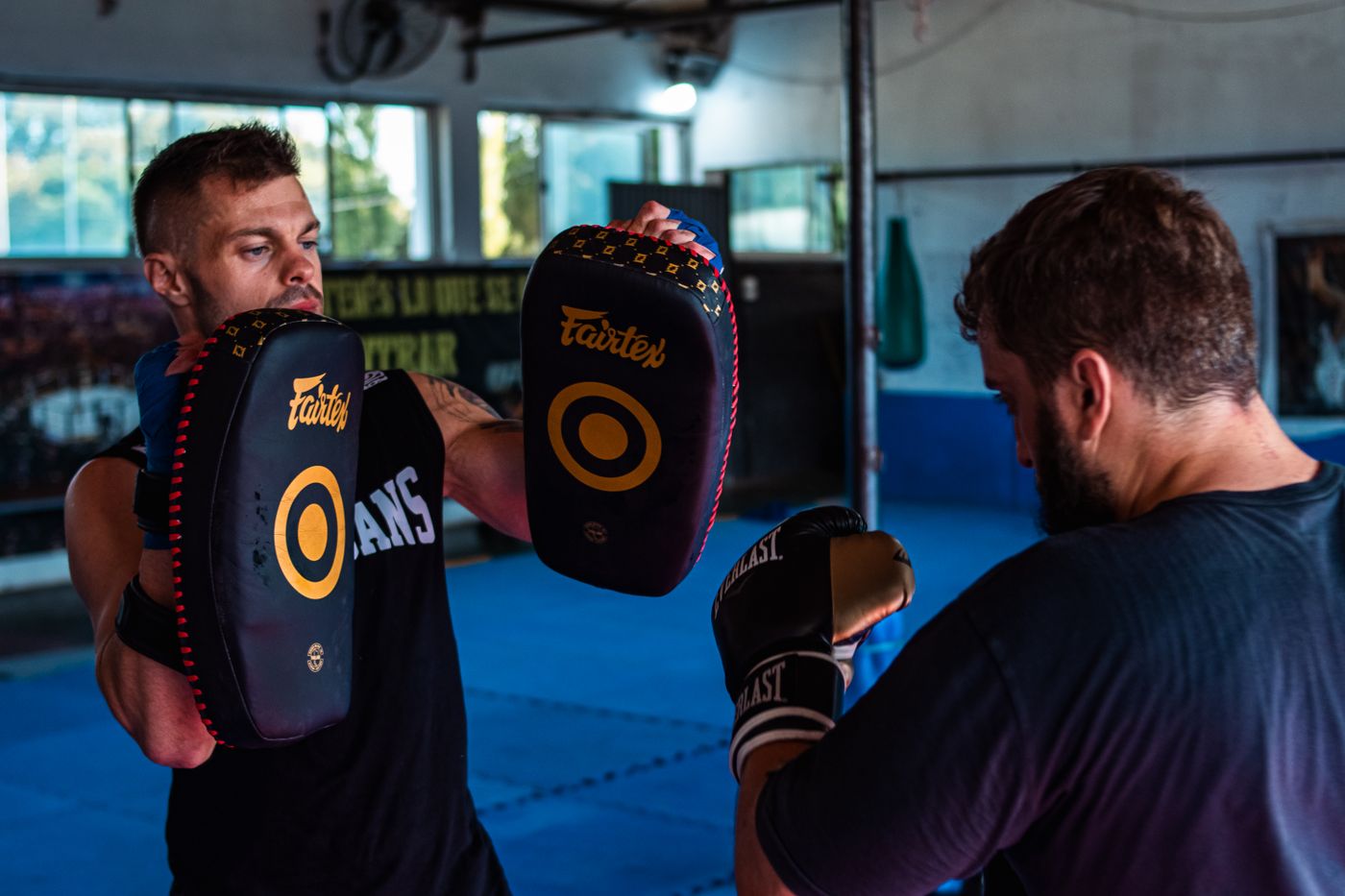 Adult kickboxers moving and training together with pads.