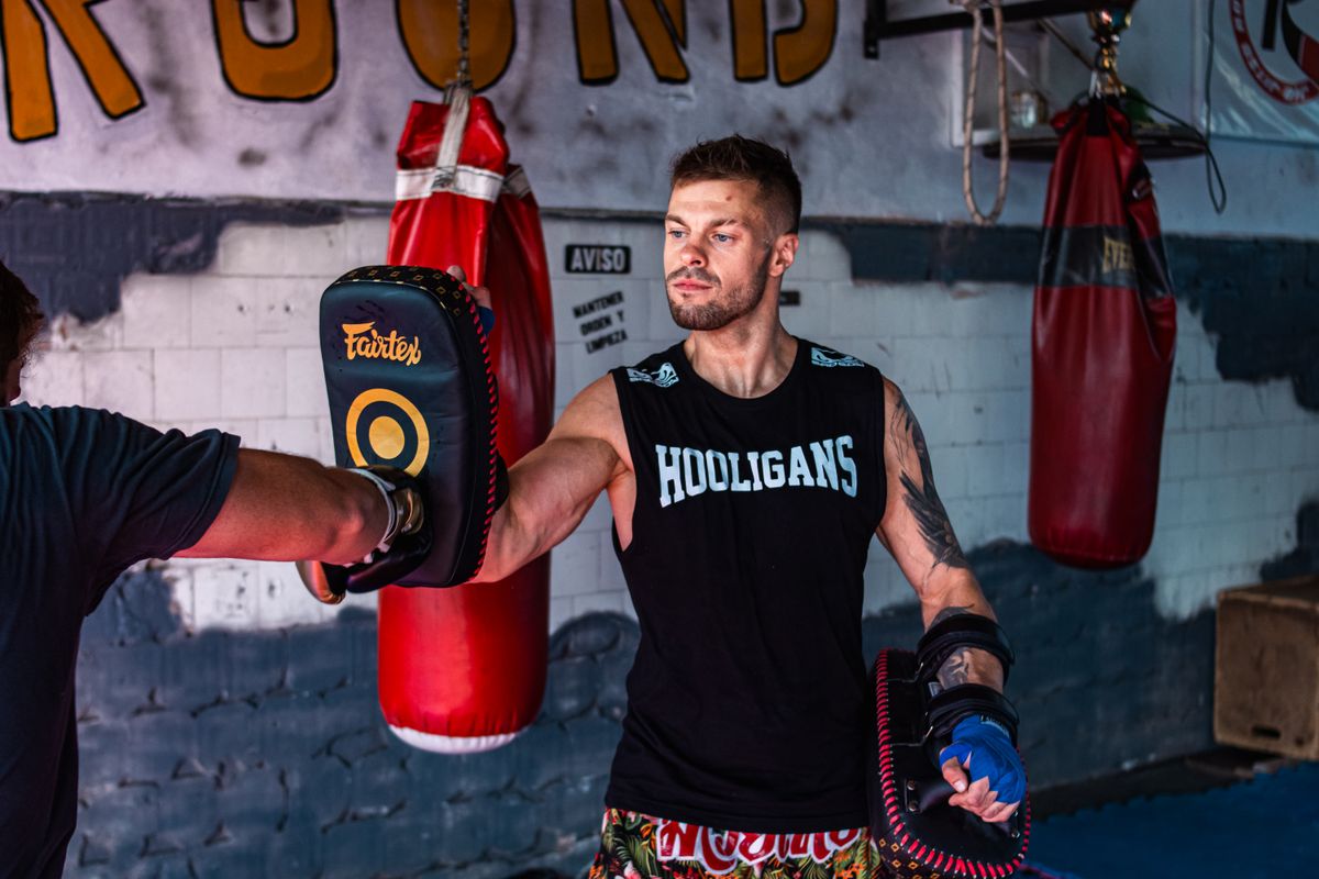 Adult kickboxers training together with pads in a martial arts gym.