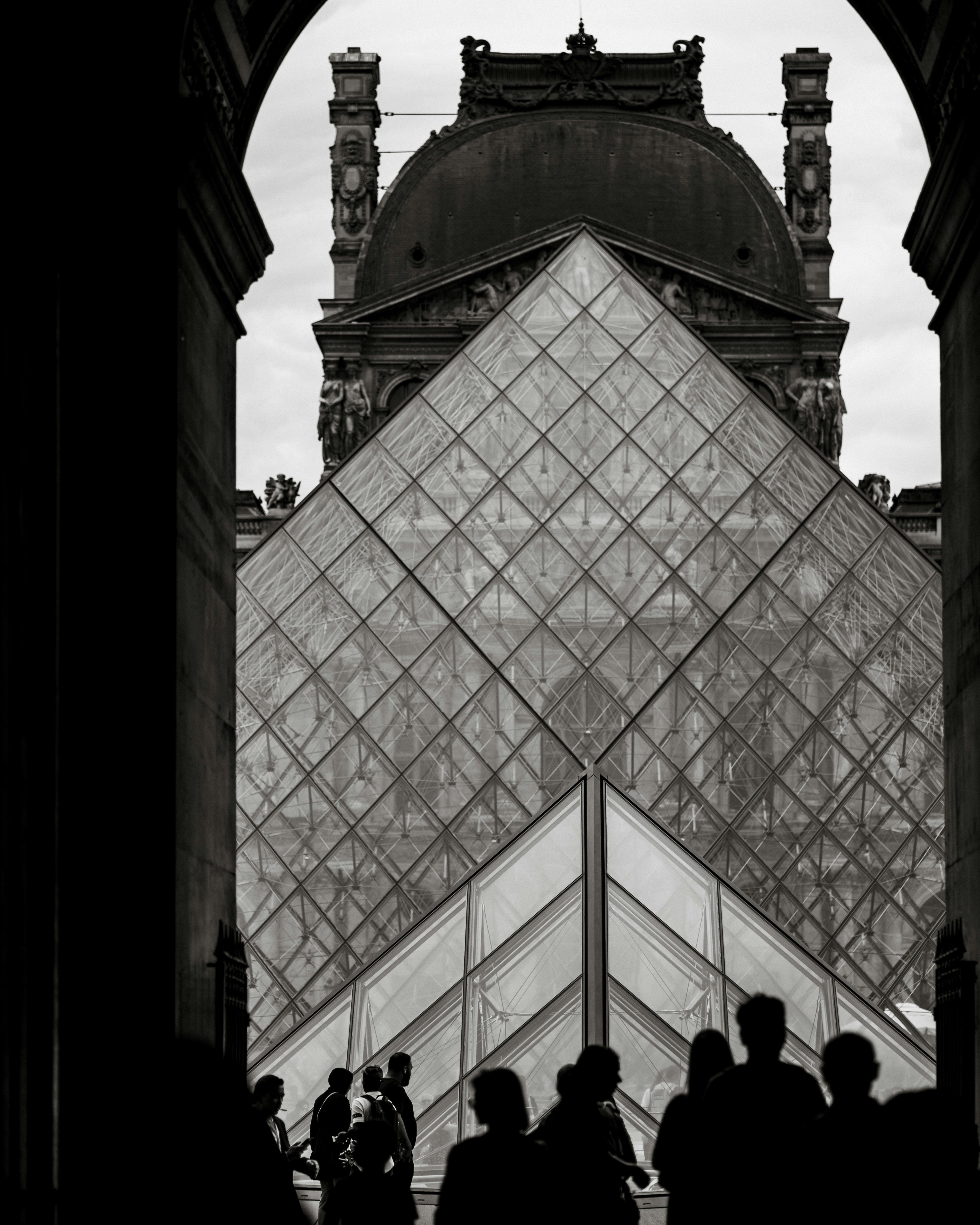 silhouettes of people walking near the louvre pyramid paris france