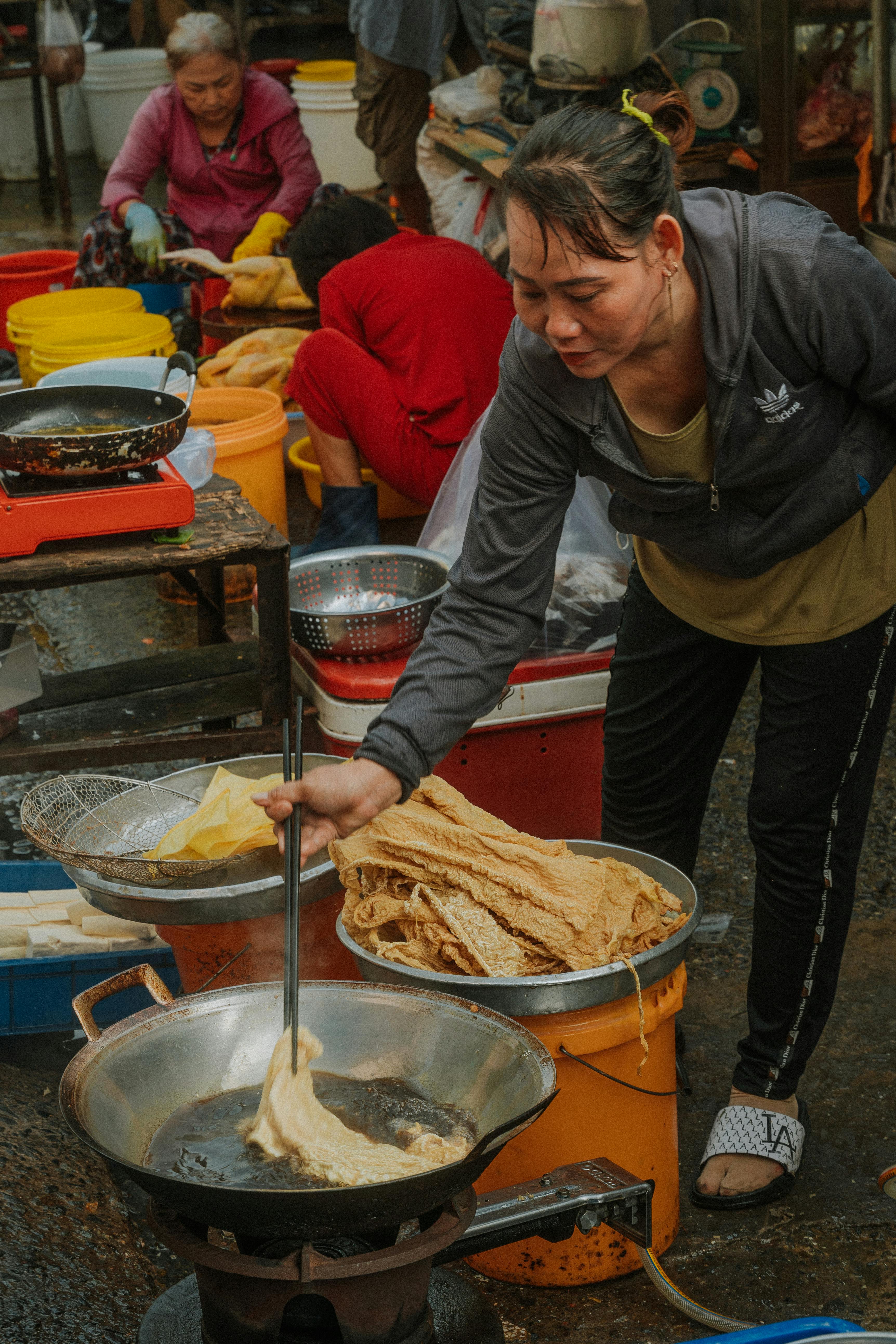 Vendor frying food at a bustling street market in Ho Chi Minh City, Vietnam.