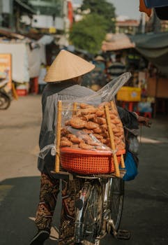 A woman selling traditional food on a bicycle in Ho Chi Minh City market.