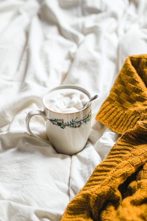 Coffee and a sweater on a bed