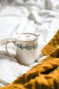 A cup of coffee on a bed with a blanket