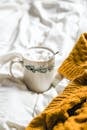 A cup of coffee on a bed with a sweater