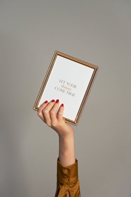 A person holding up a framed picture with the words'you are beautiful'
